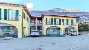 A building with a yellow facade, multiple windows, and a car parked in front. - Cosy apartment for 2 guests with WIFI, TV and balcony (Dongo)