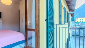 A bedroom with a bed, a wardrobe, and a balcony with shutters. - Cosy apartment for 2 guests with WIFI, TV and balcony (Dongo)