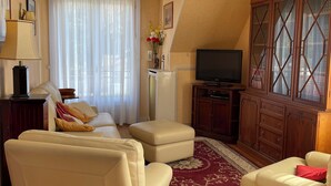 Ein Wohnzimmer mit einer Couch, einem Hocker, einem Fernseher und einem Holzschrank.