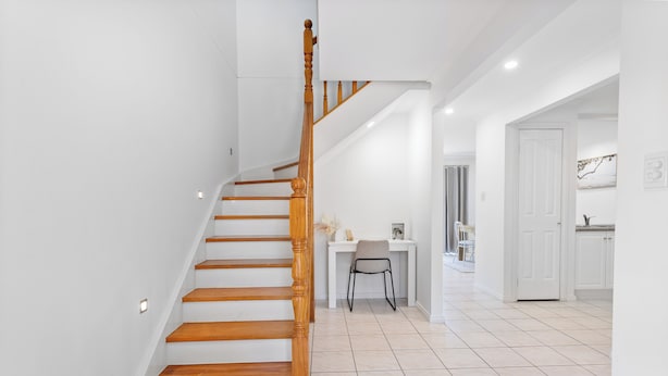 A staircase with wooden steps and a wooden handrail leading to a landing.