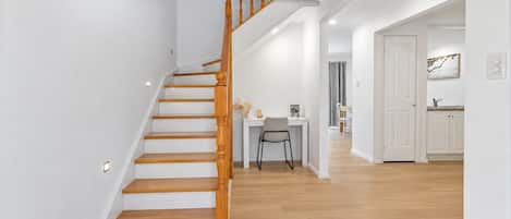 A staircase with wooden balusters leading to a dining area with a table and chairs.
