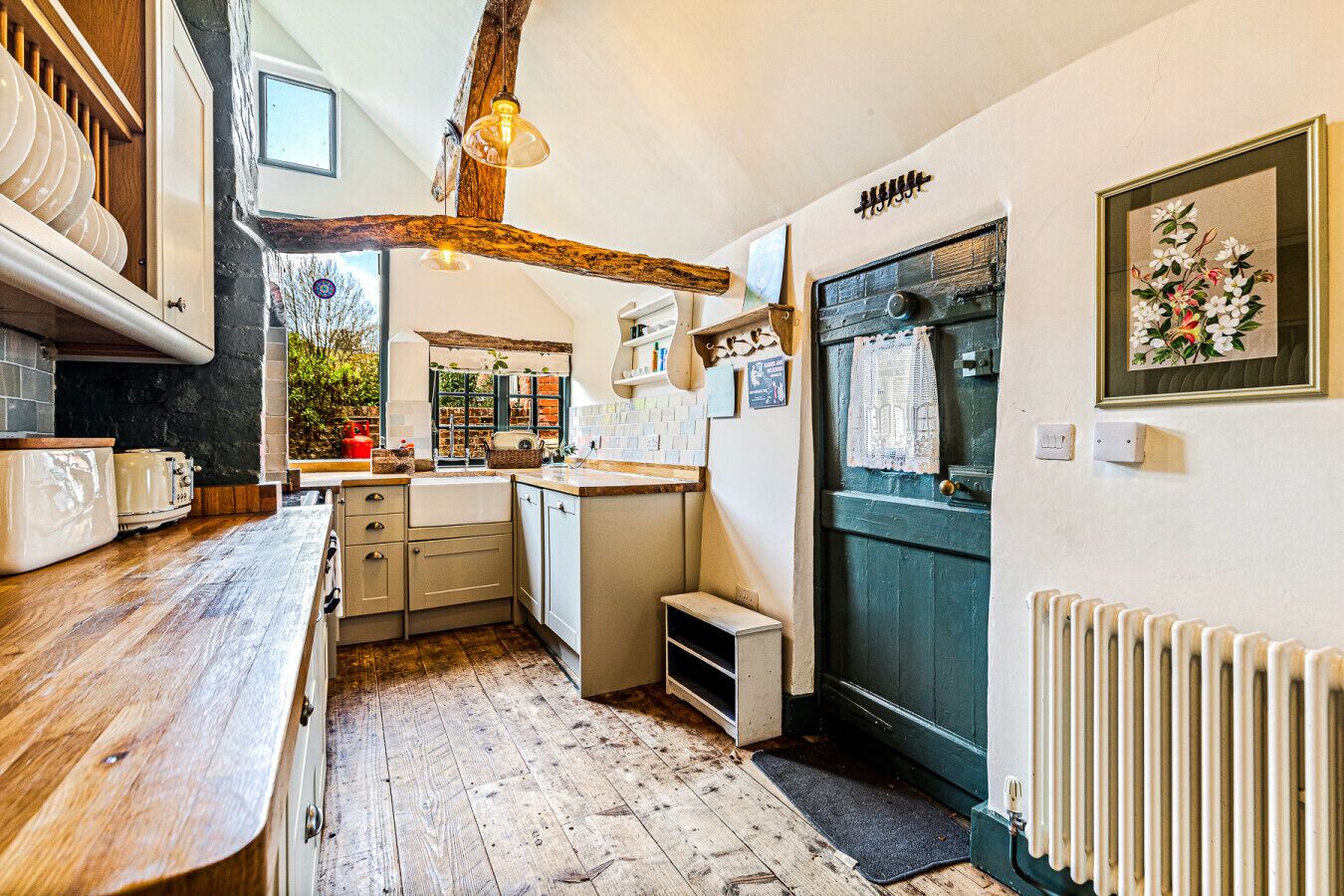A compact kitchen with wooden countertops, a built-in oven, and a rustic ceiling.