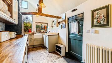 A compact kitchen with wooden countertops, a built-in oven, and a rustic ceiling.