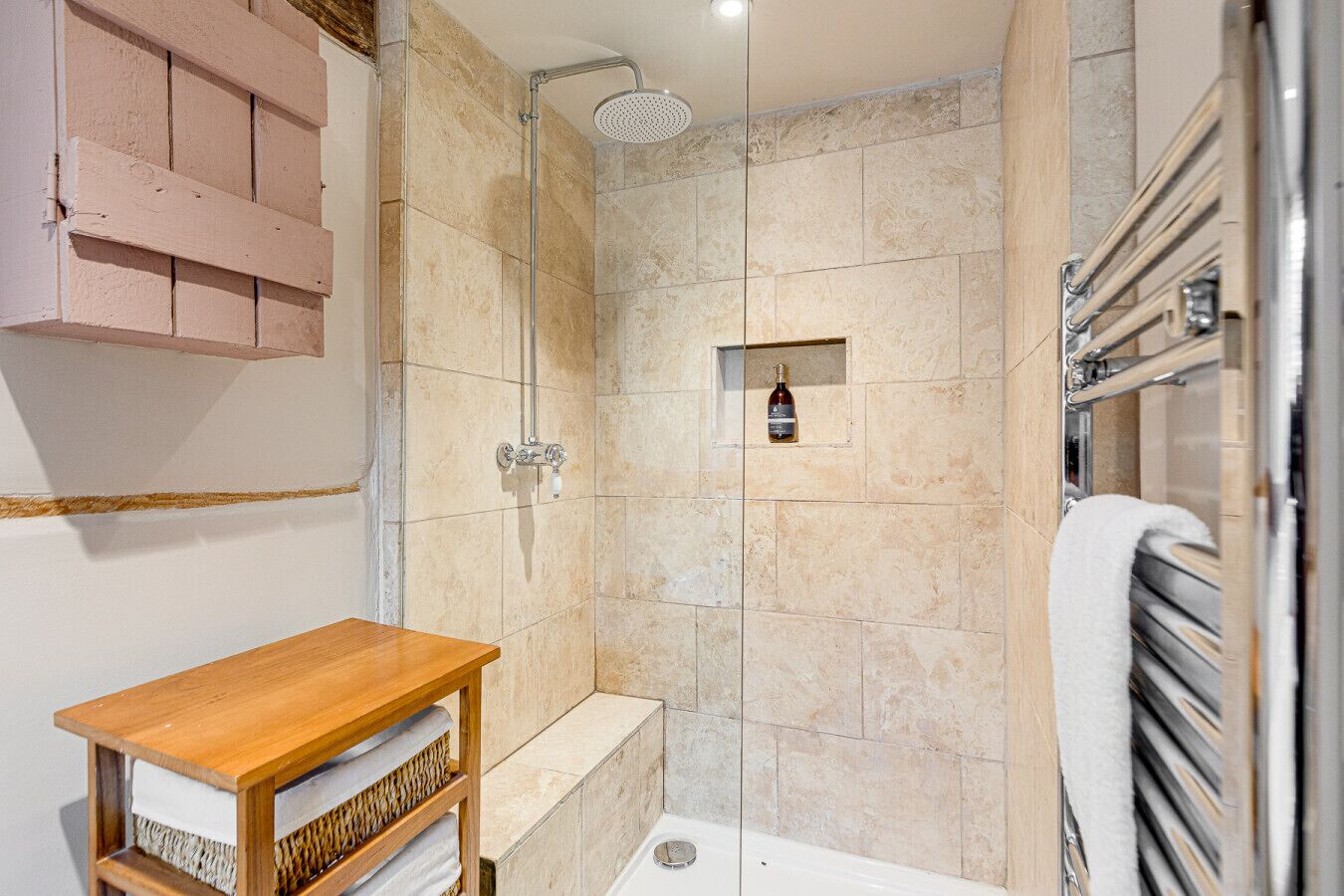 Une salle de bain moderne avec une douche, une étagère en bois et un porte-serviettes.