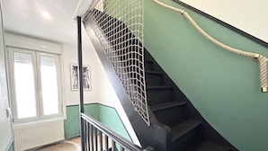 A staircase with a metal safety net, a handrail, and a rope on the side. - Apart'Moment EN GROUPE - Le Cocon du Haut-Pont (Saint-Omer)