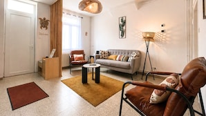 A modern living room with a sofa, armchair, coffee table, and floor lamp. - Apart'Moment EN GROUPE - Le Cocon du Haut-Pont (Saint-Omer)
