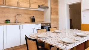 A modern kitchen with wooden cabinets, a stainless steel sink, and a dining table set for four. - Apart'Moment EN GROUPE - Le Cocon du Haut-Pont (Saint-Omer)