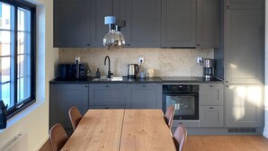 A modern kitchen with grey cabinets, a wooden dining table, and a built-in oven. - Stunning apartment in Idre with sauna (Idre)
