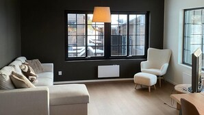 A modern living room with a large window, a sofa, a chair, and a table. - Stunning apartment in Idre with sauna (Idre)