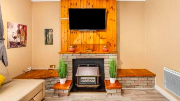 Ein Wohnzimmer mit Kamin, einem flachbildfernseher darüber und einem Sofa.