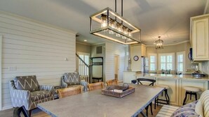 A spacious kitchen with a long island, pendant lighting, and a view of the living area.