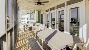 A covered outdoor area with a table and chairs, a ceiling fan, and a view of the surrounding buildings.