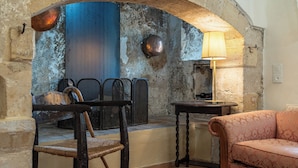 A cozy room with a stone archway, a wooden chair, a sofa, and a table with a lamp. - The Olive Mill House Luxe Villa (Rethymno)