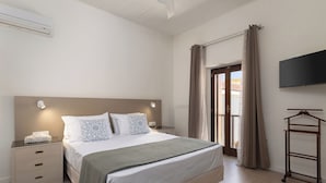 A neatly arranged bedroom with a bed, bedside table, and a TV mounted on the wall. - The Olive Mill House Luxe Villa (Rethymno)