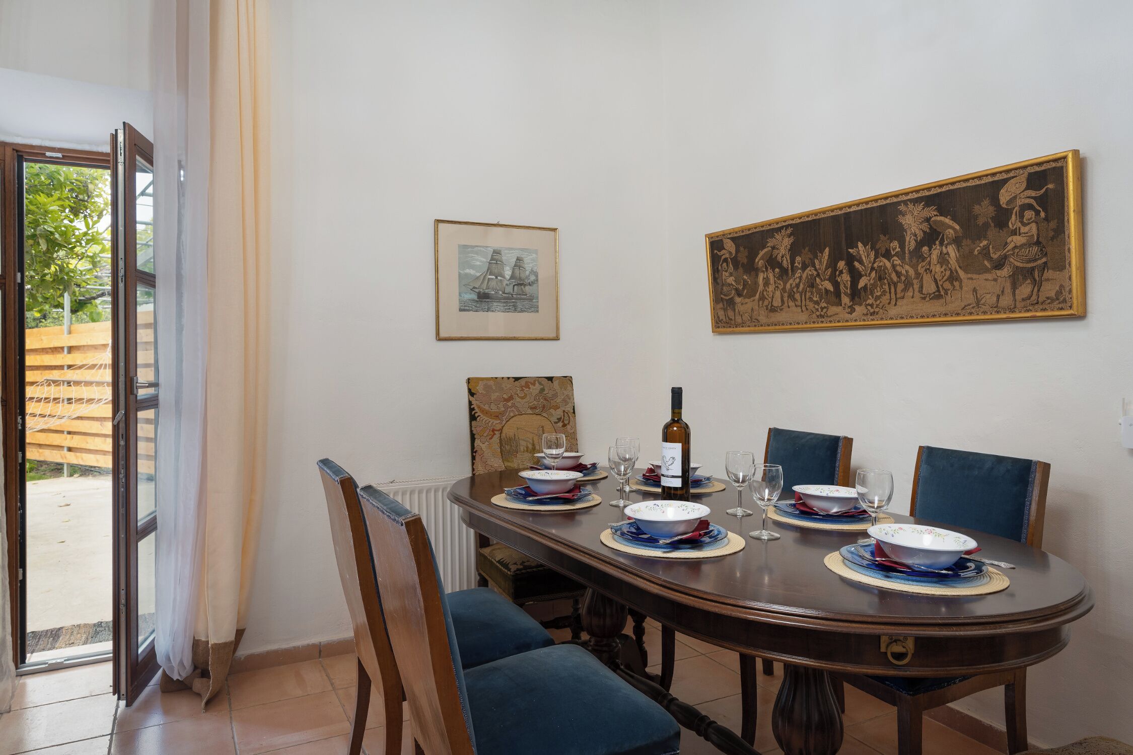 A dining table set with plates, bowls, wine glasses, and a bottle, surrounded by chairs.