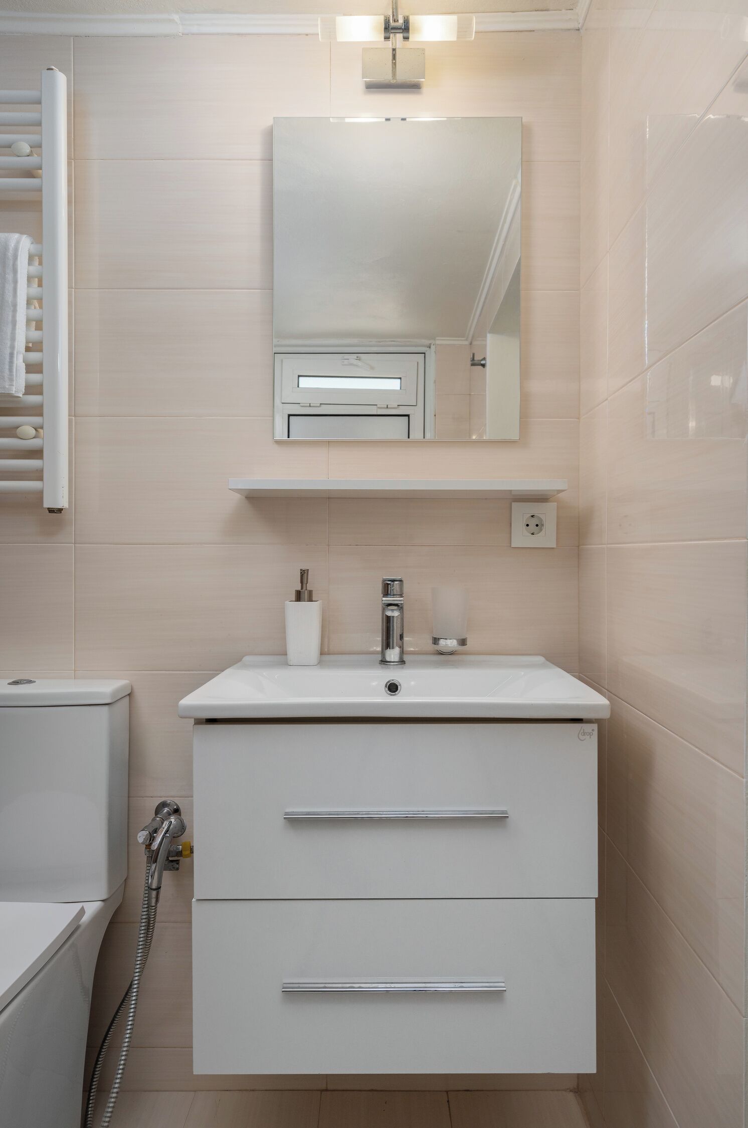 Un baño moderno con tocador blanco, espejo y barra para toallas.