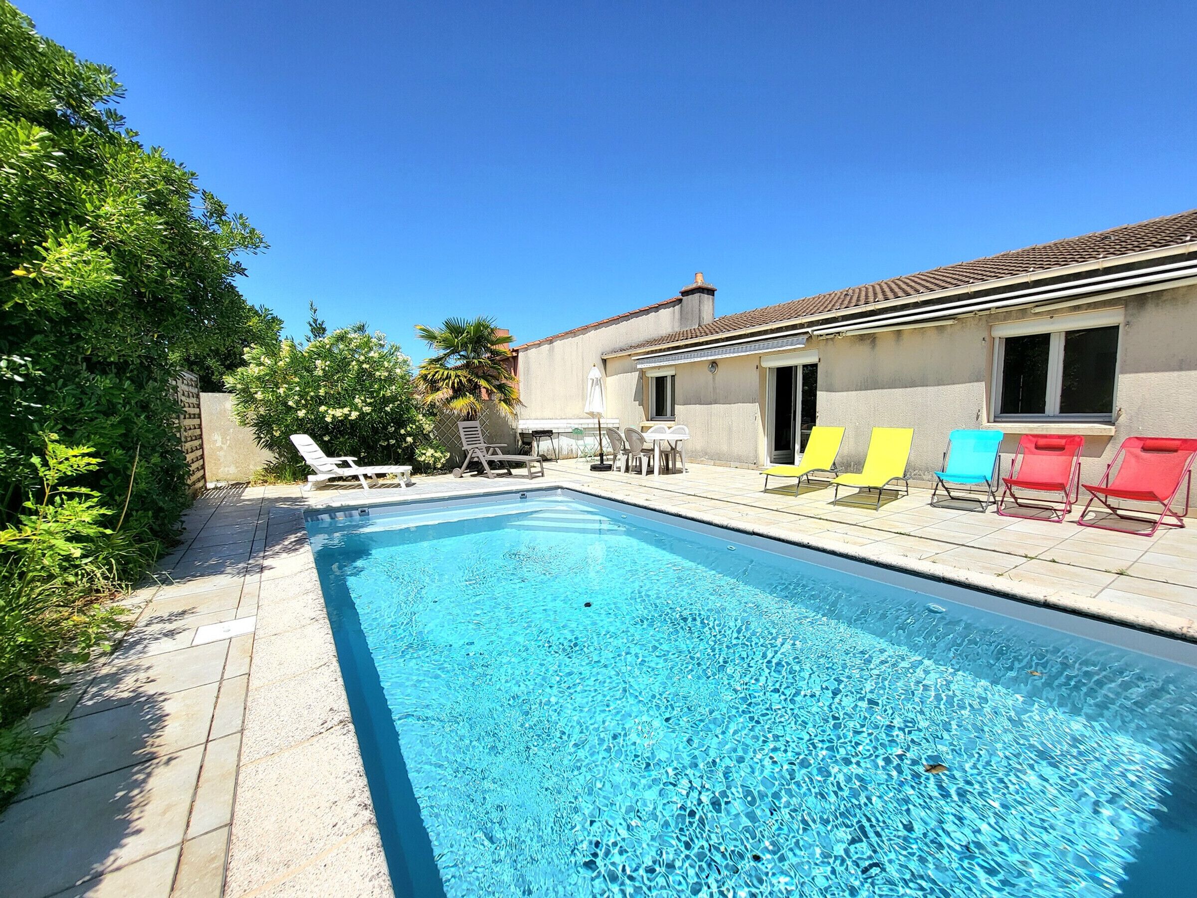 A swimming pool with lounge chairs, a patio area, and a building with a tiled roof.