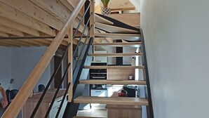 A wooden staircase with black railings leading to a kitchen area.