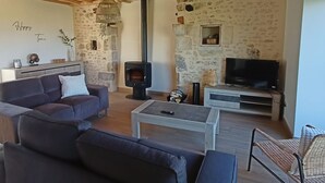 A cozy living room with a stone wall, a fireplace, a sofa, a coffee table, and a TV.