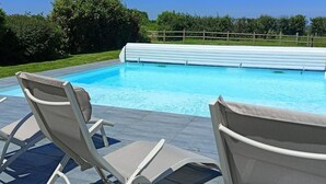 A swimming pool with lounge chairs and a wooden deck.