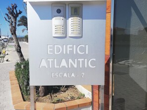 A sign for 'EDIFICI ATLANTIC ESCALA - 2' with two control panels above it.