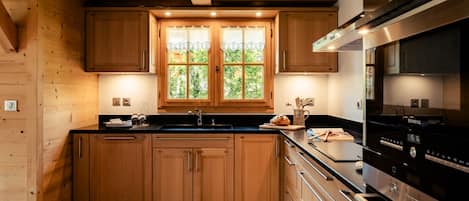 Une cuisine moderne avec des meubles en bois, un plan de travail noir et des appareils électroménagers en acier inoxydable.