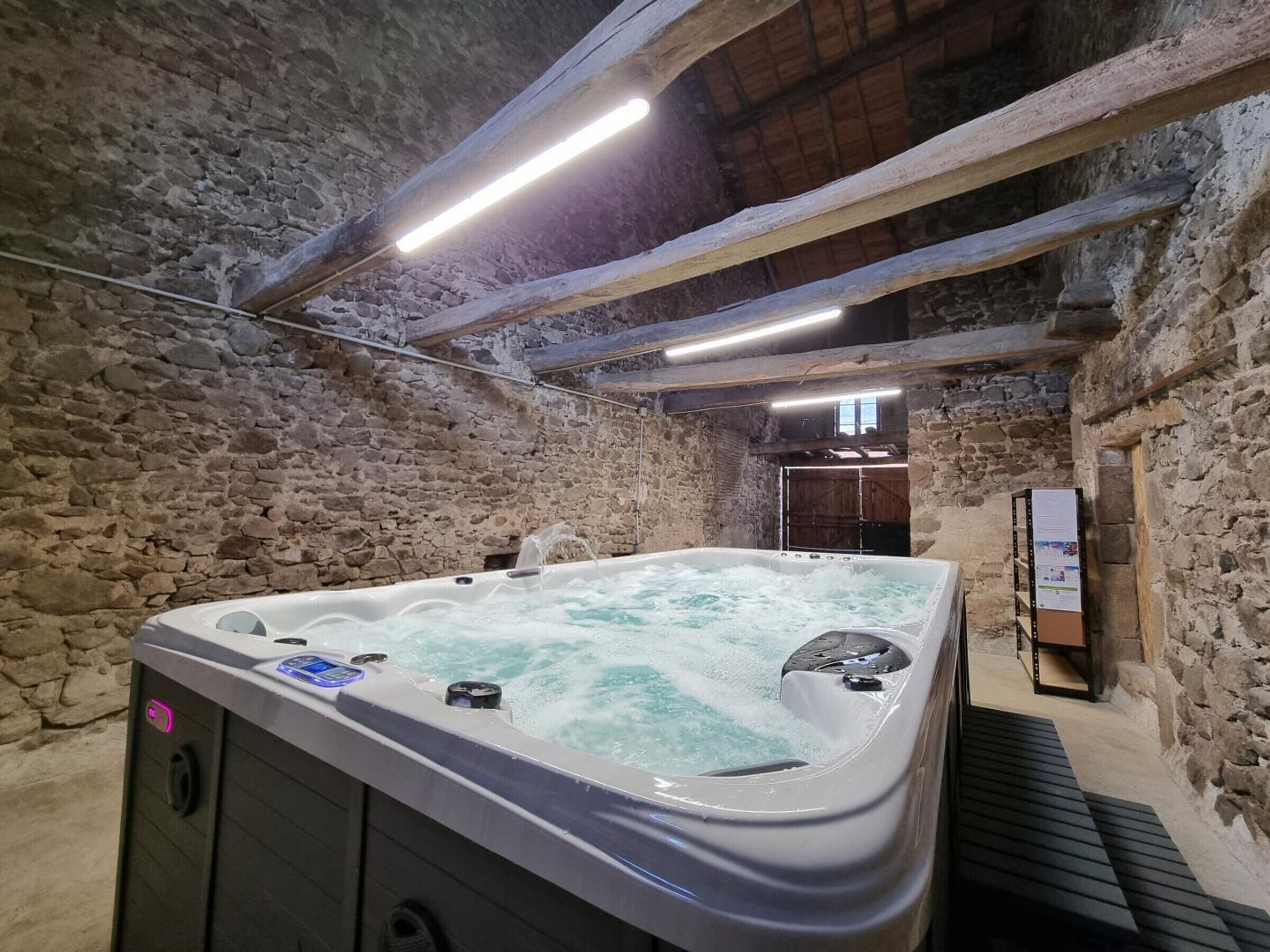 A stone-walled room with a hot tub.