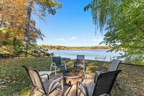 Un patio junto al lago con mobiliario exterior y una chimenea.
