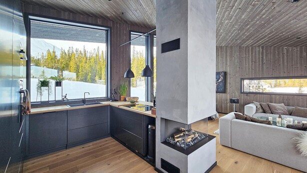 A modern kitchen with a large window, a built-in stove, and a cozy seating area with a couch and a coffee table.