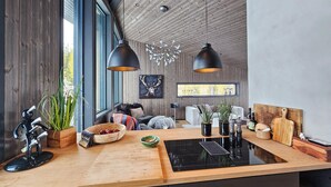 A modern kitchen with a wooden countertop, black appliances, and pendant lighting.