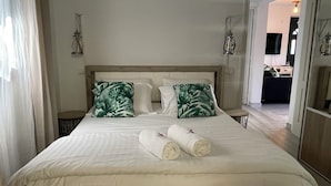 A neatly made bed with two pillows, a bedside table, and a lamp.