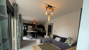 A modern living room with a sofa, a coffee table, and a kitchen in the background.