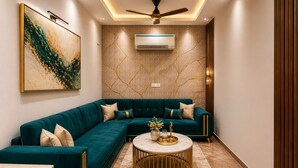 A modern living room with a sectional sofa, a round coffee table, and a ceiling fan. - Hotel Palm View by JMD Group (New Delhi)