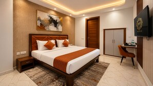 Une chambre d’hôtel moderne équipée d’un grand lit, d’un bureau, d’une armoire et d’un téléviseur.