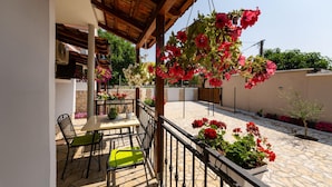 Un espace extérieur abrité, aménagé avec une table et des chaises, et entouré de plantes et de fleurs en pot.