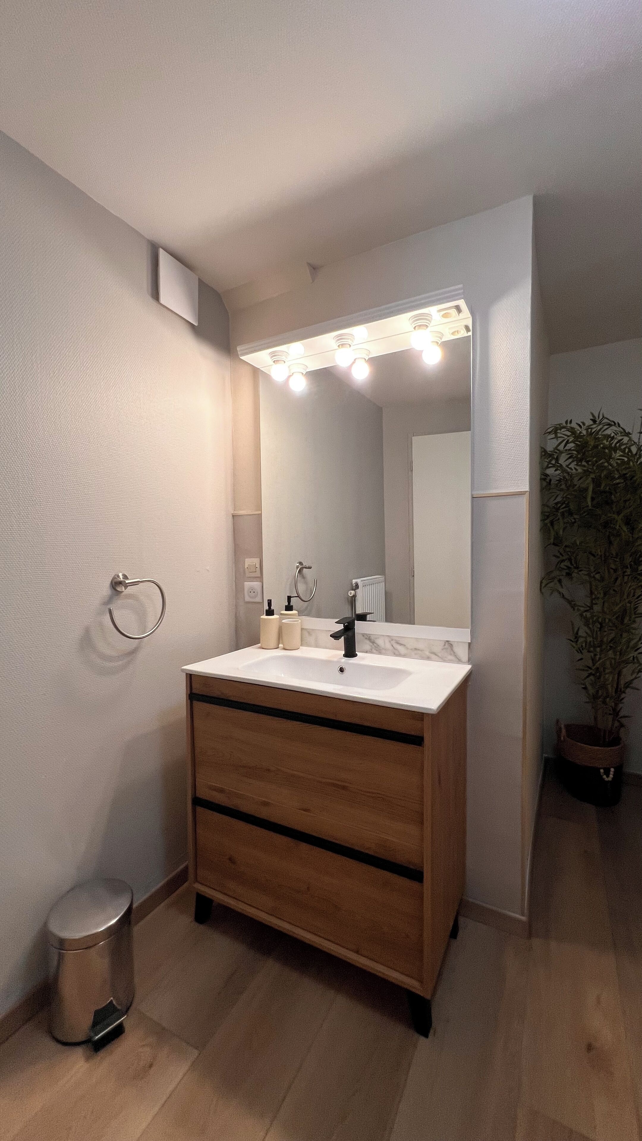 Ein modernes Badezimmer mit Waschtisch, Spiegel und Beleuchtung.