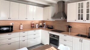 A modern kitchen with white cabinets, a wooden countertop, and stainless steel appliances. - Apartment in the heart of the High Vosges! (Cornimont)