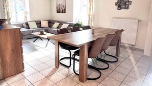 A spacious living area with a dining table, a sofa, and a radiator. - Apartment in the heart of the High Vosges! (Cornimont)