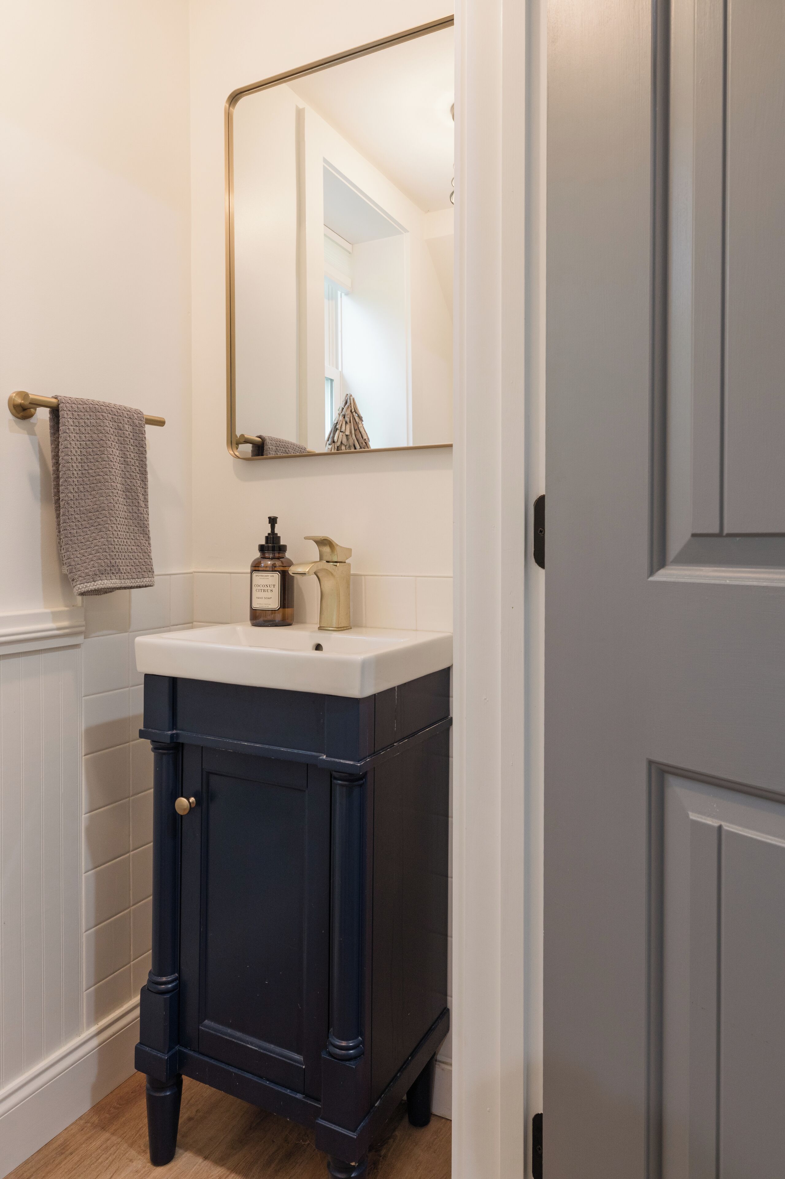A bathroom with a dark wooden vanity, a white sink, and a gold faucet.