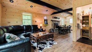 A cozy cabin interior with a leather sofa, wooden coffee table, and a fireplace. - The Mont Haus- WOOD FIRED SAUNA - Minutes to Mt. Snow and Stratton! (Wardsboro)