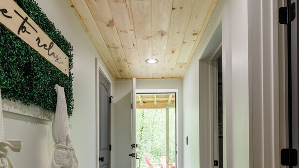 A hallway with a bench, a wall-mounted towel rack, and a door leading to an outdoor area. - The Mont Haus- WOOD FIRED SAUNA - Minutes to Mt. Snow and Stratton! (Wardsboro)