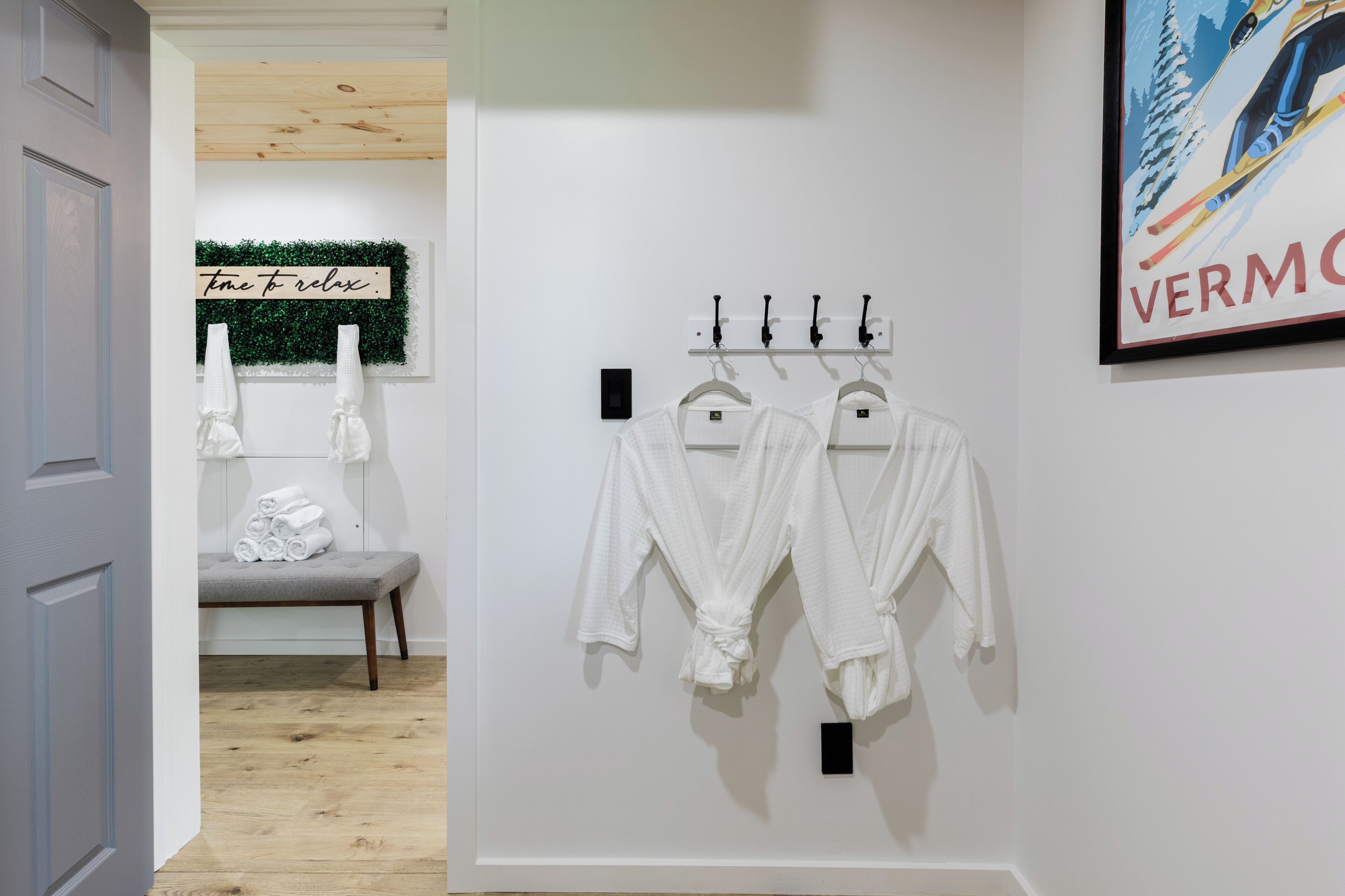 A room with a bench, a wall-mounted towel rack with white towels, and a sign that says "time to relax."