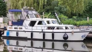 Een witte boot genaamd 'Tranquillou' afgemeerd aan een steiger met een blauw zonnedak en een kajuit.