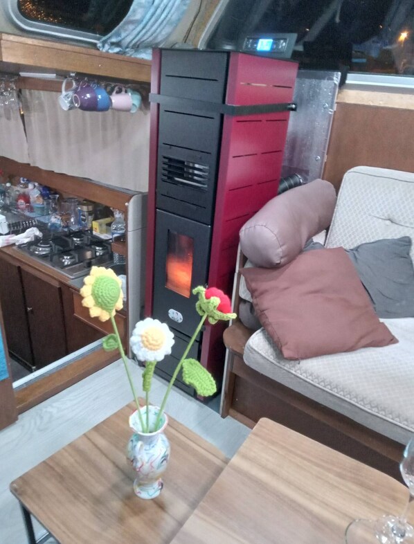 A cozy interior with a sofa, a small table with a vase of flowers, and a kitchen area with a stove and cabinets. - Nice boat at dock (Pontrieux)