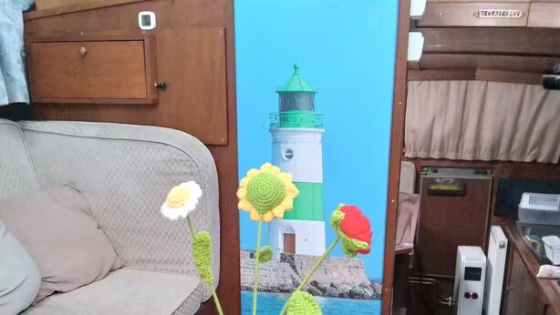 Een gezellig interieur met een houten bank, een tafel met een glas witte wijn, een glas melk en een gehaakte bloemstelling.