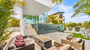 A modern outdoor patio with a fire feature, seating, and a stone wall.