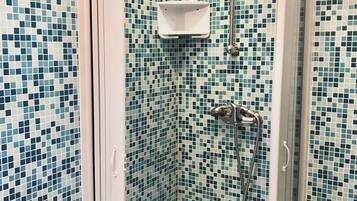 A shower with a glass door, tiled walls, and a handheld showerhead.