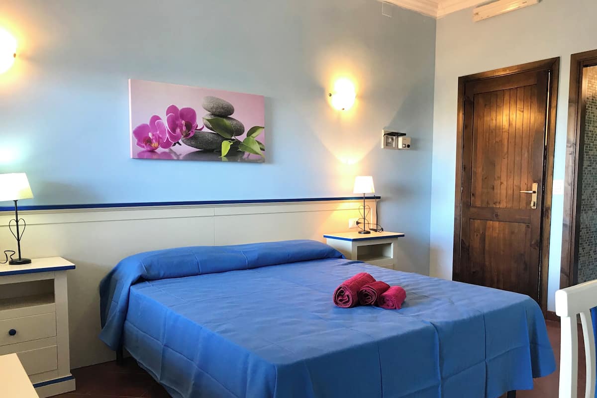Ein Hotelzimmer mit einem Bett, zwei Nachttischen, einer Ablage und einer Wandleuchte.