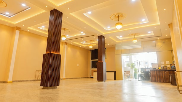 A spacious lobby with a modern design, featuring a tall, textured column, recessed lighting, and a reception desk. - B&B Estrella Hotel And Resort  (Indore)