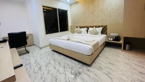A modern hotel room with a large bed, a desk, a chair, and a window. - B&B Estrella Hotel And Resort  (Indore)